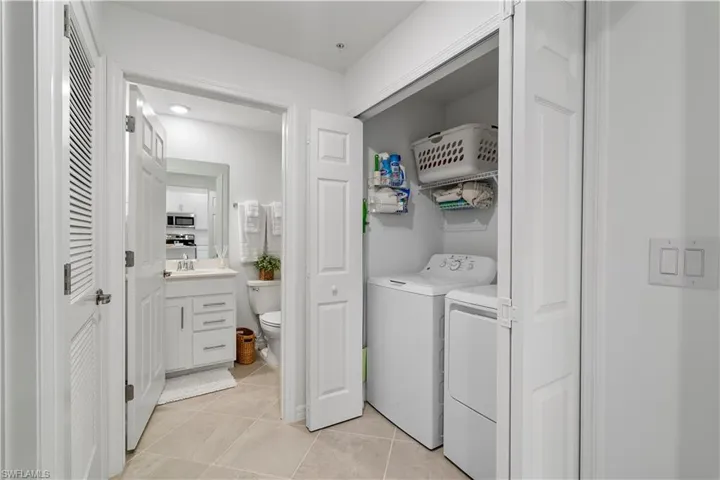 Laundry area featuring light tile patterned flooring and washer and clothes dryer