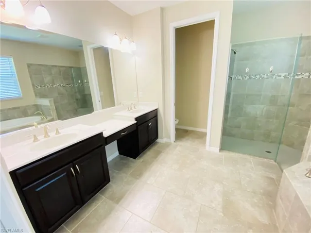 Full bathroom featuring a bath, double vanity, a walk in shower, and light tile patterned floors