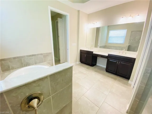 Bathroom featuring double vanity, a garden tub, light tile patterned flooring, and an enclosed shower