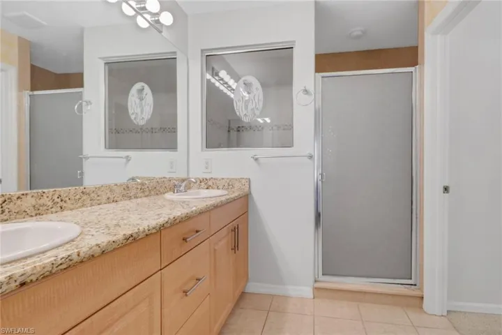 Full bathroom featuring double vanity, light tile patterned floors, a large walk in shower, and a walk in closet