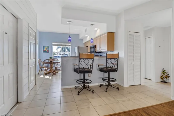 Kitchen featuring a breakfast bar area, pendant lighting, light tile patterned flooring, a peninsula, and backsplash
