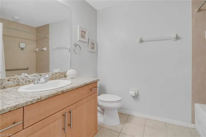 Bathroom with light tile patterned floors, vanity, and bath tub and shower combination