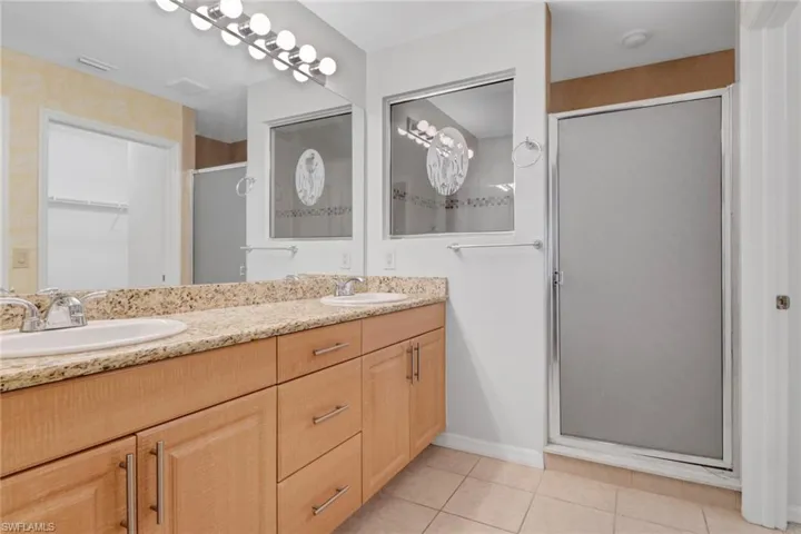 Full bathroom featuring double vanity, light tile patterned floors, a large walk in shower, and a walk in closet