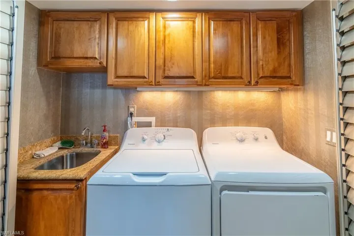 Washroom with washing machine and clothes dryer, cabinet space, and bar with sink