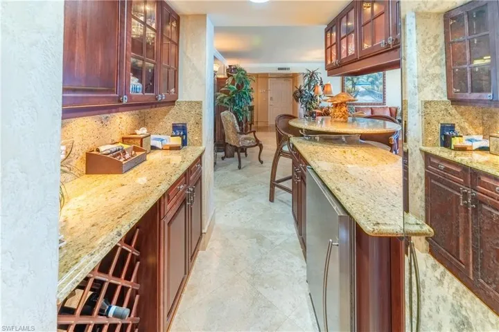 Kitchen featuring tasteful backsplash, light stone countertops, and glass insert cabinets