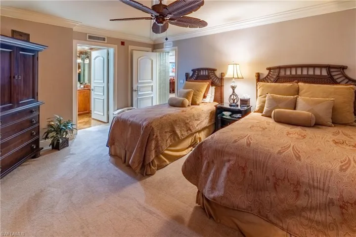 Bedroom with light carpet, crown molding, ensuite bath, and a ceiling fan
