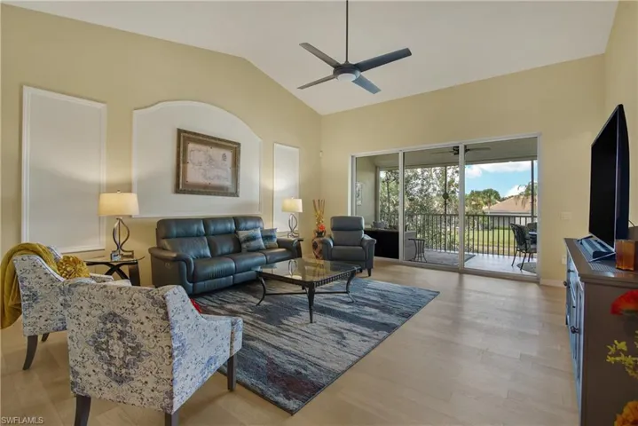 Living room with ceiling fan, light wood finished floors, and high vaulted ceiling