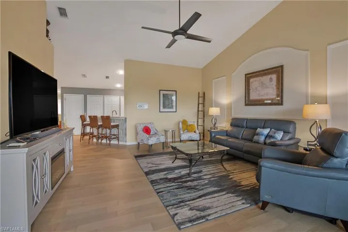 Living room featuring light wood finished floors, a ceiling fan, and high vaulted ceiling