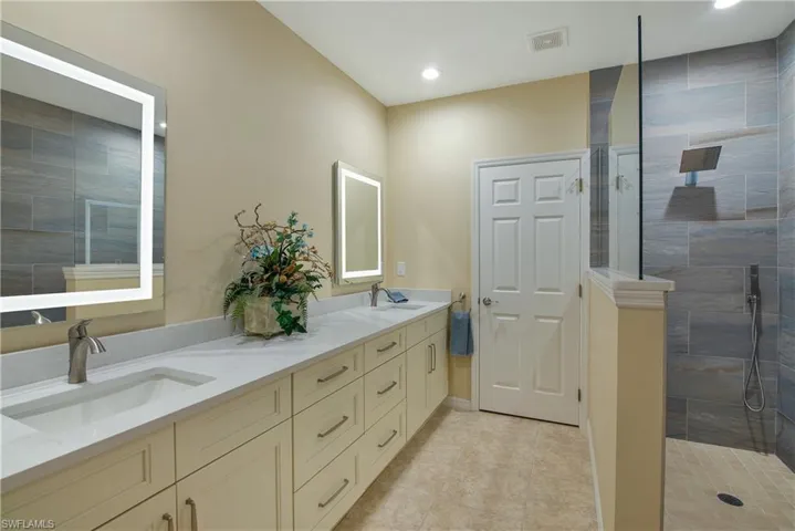 Bathroom featuring a walk in shower, double vanity, recessed lighting, and light tile patterned floors