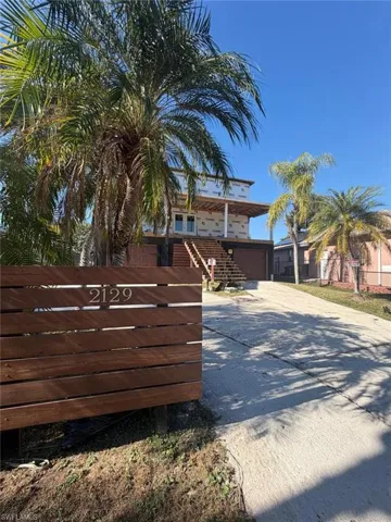 View of front of property with concrete driveway, a garage, stairs, and a balcony