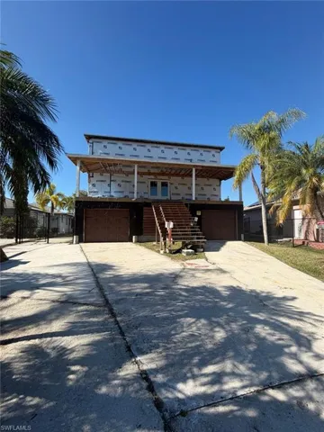Unfinished property featuring driveway, a balcony, stairway, and a garage