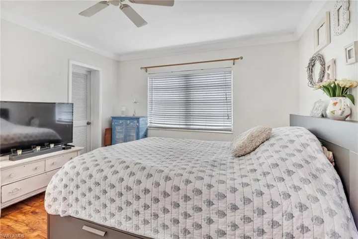 Bedroom with ornamental molding, ceiling fan, and light wood-type flooring