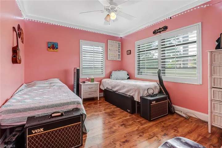Bedroom with ornamental molding, ceiling fan, and dark hardwood / wood-style flooring