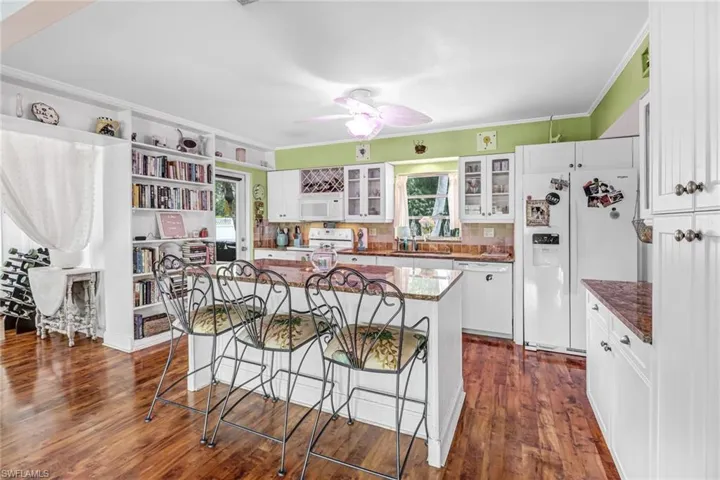 Kitchen featuring white cabinets, dark hardwood / wood-style flooring, white appliances, and a kitchen island