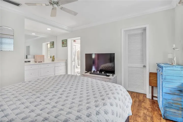 Bedroom with crown molding, ceiling fan, wood-type flooring, ensuite bathroom, and multiple windows