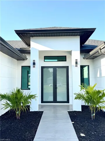 View of exterior entry with stucco siding, french doors, and roof with shingles