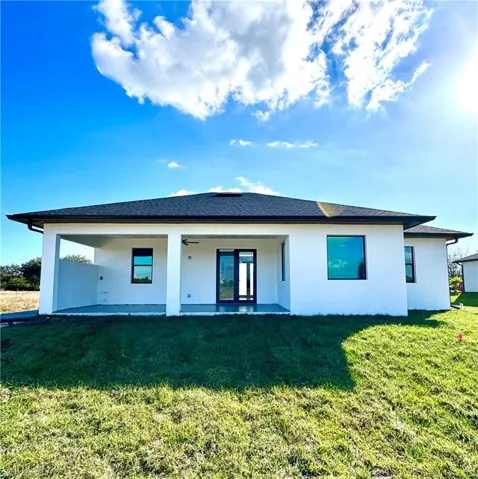 Rear view of property featuring a patio area, ceiling fan, and a lawn