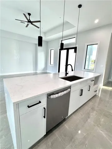 Kitchen with marble finish floor, a sink, a raised ceiling, a large island, and dishwasher