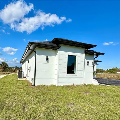 View of side of property featuring a lawn and central air condition unit