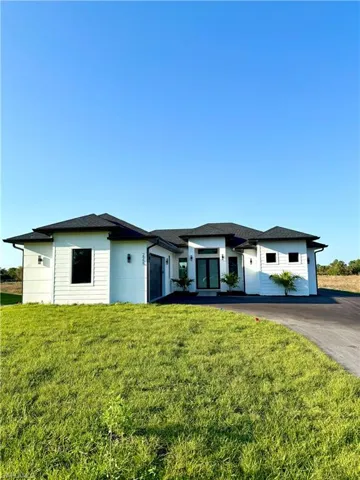Prairie-style home with driveway, an attached garage, and a front lawn