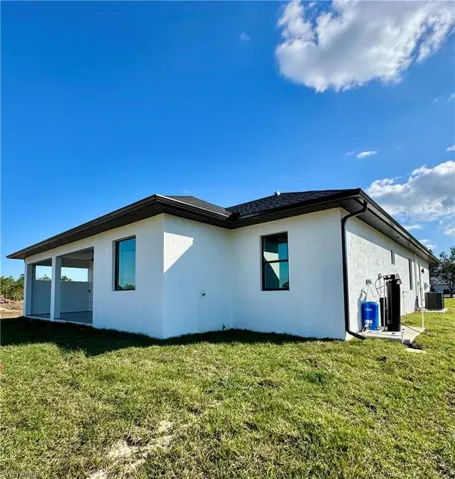 Back of house with cooling unit and a yard