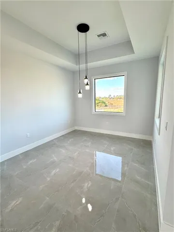 Unfurnished room with marble finish floor, baseboards, visible vents, and a raised ceiling