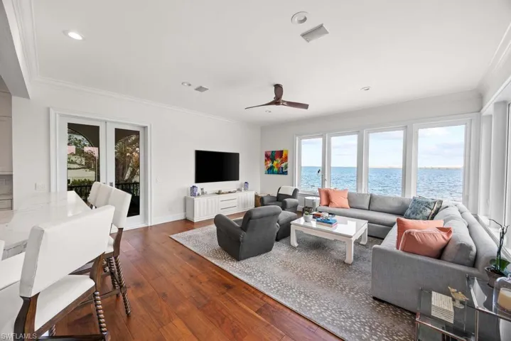 Living room featuring crown molding, dark wood-type flooring, ceiling fan, and french doors