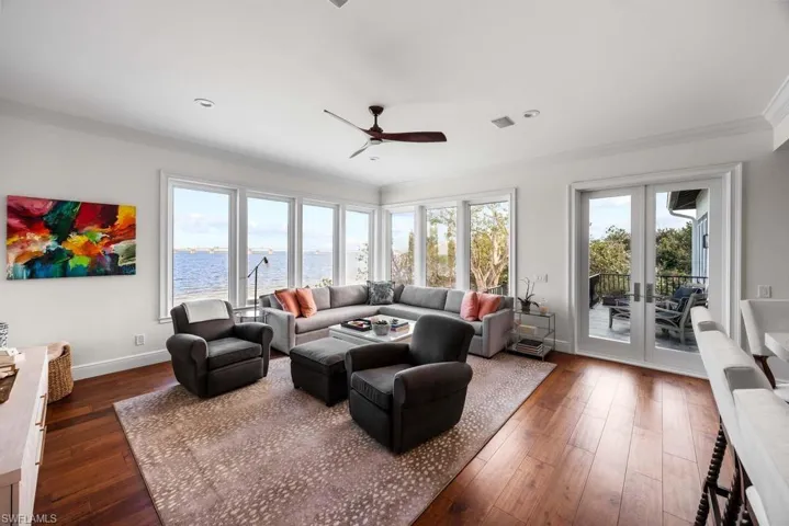 Living room with dark wood-type flooring, french doors, a water view, crown molding, and ceiling fan