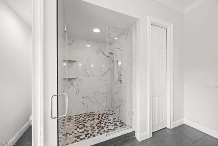Bathroom featuring crown molding, tile patterned floors, toilet, and an enclosed shower