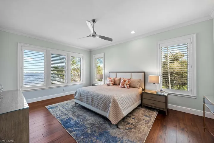 Bedroom featuring dark wood-type flooring, ceiling fan, and ornamental molding