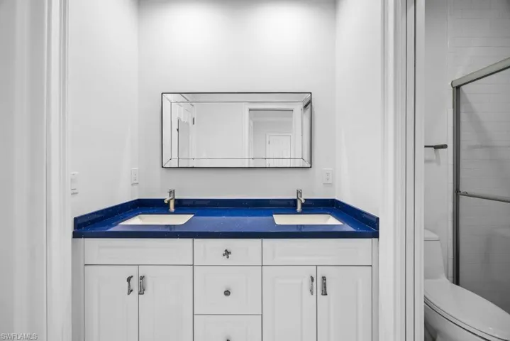 Bathroom featuring vanity, a shower with shower door, and toilet
