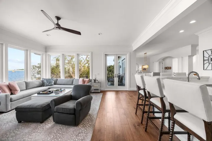 Living room featuring hardwood / wood-style flooring, ornamental molding, ceiling fan, a water view, and french doors