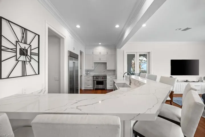 Kitchen featuring high end appliances, sink, a breakfast bar area, and white cabinets