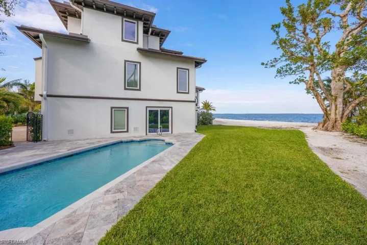 Rear view of house featuring a patio area, a lawn, and a water view