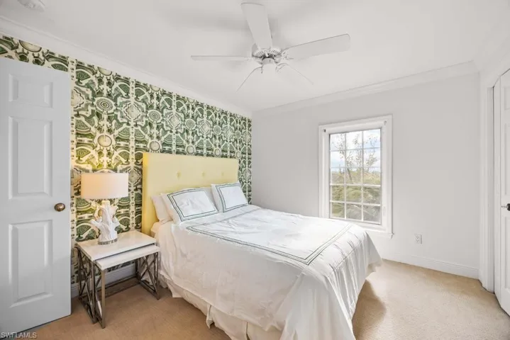 Bedroom with light carpet, ornamental molding, and ceiling fan