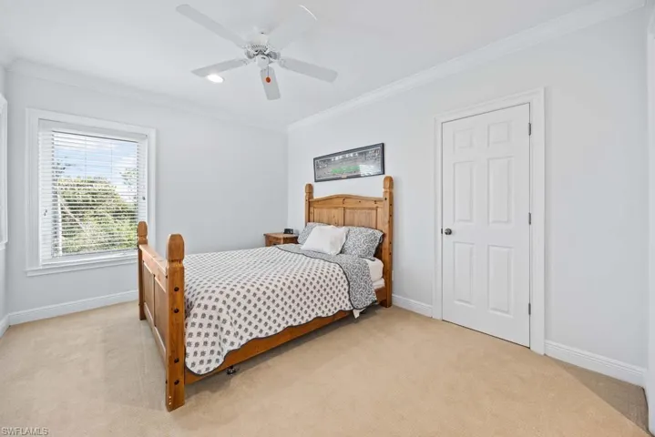 Bedroom featuring crown molding, light colored carpet, and ceiling fan
