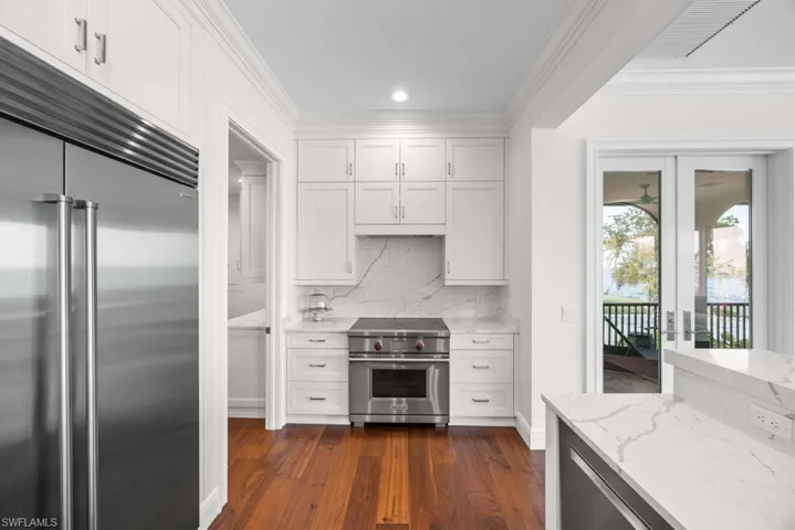 Kitchen featuring white cabinetry, ornamental molding, high quality appliances, and light stone countertops
