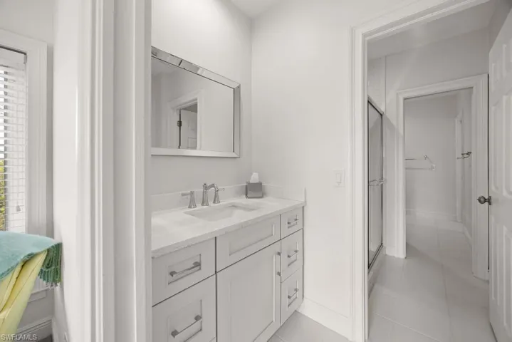 Bathroom featuring tile patterned floors, vanity, and a shower with door