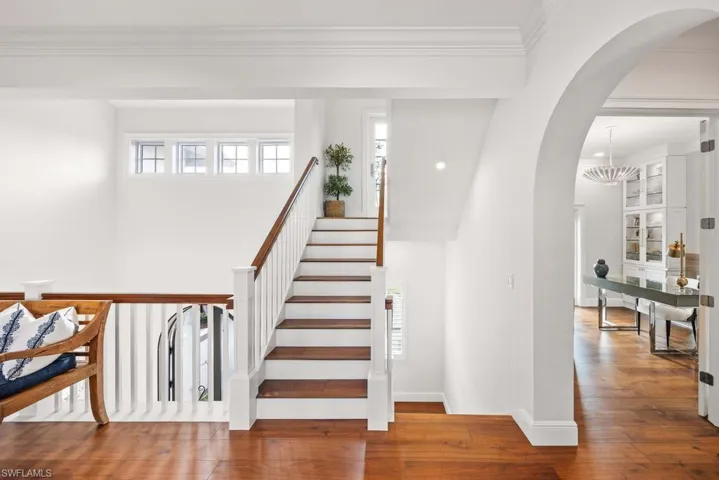 Stairs with hardwood / wood-style flooring, crown molding, and an inviting chandelier