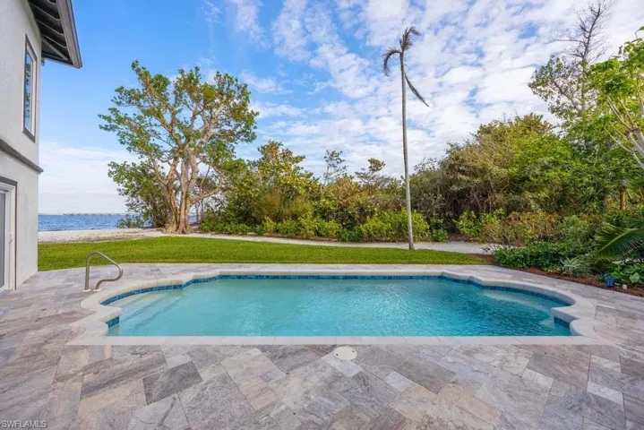 View of pool with a patio area, a lawn, and a water view