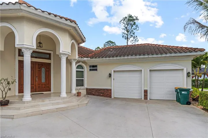 View of front of property with a garage, a tile roof, driveway, stucco siding, and stone siding