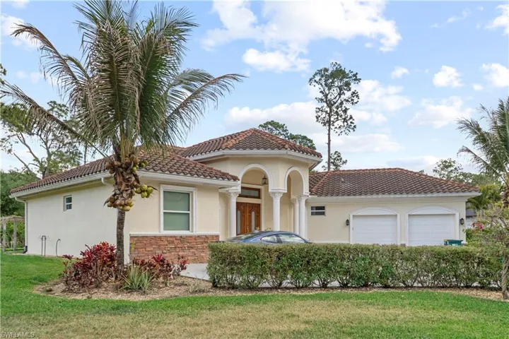 Mediterranean / spanish-style home featuring stucco siding, an attached garage, a tile roof, and a front lawn