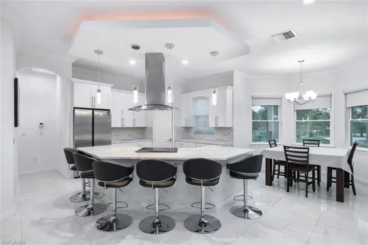 Kitchen featuring island exhaust hood, white cabinets, crown molding, a large island, and freestanding refrigerator