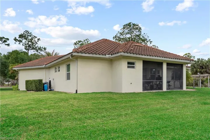 Back of house with stucco siding, a yard, a tile roof, and a sunroom