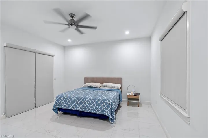Bedroom featuring a ceiling fan, recessed lighting, and light marble finish floors