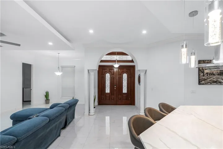 Foyer entrance with ornamental molding, arched walkways, recessed lighting, light marble finish flooring, and a ceiling fan