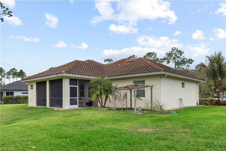 Back of property with a yard, stucco siding, a sunroom, and a tile roof