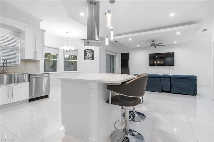 Kitchen with white cabinetry, ceiling fan, stainless steel dishwasher, island range hood, and crown molding
