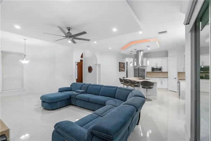 Living area with arched walkways, recessed lighting, ceiling fan, and crown molding