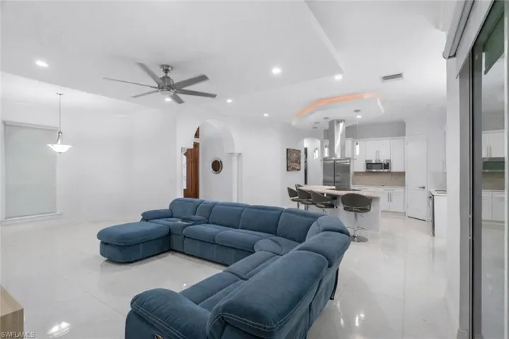 Living room with arched walkways, a ceiling fan, recessed lighting, and light tile patterned floors